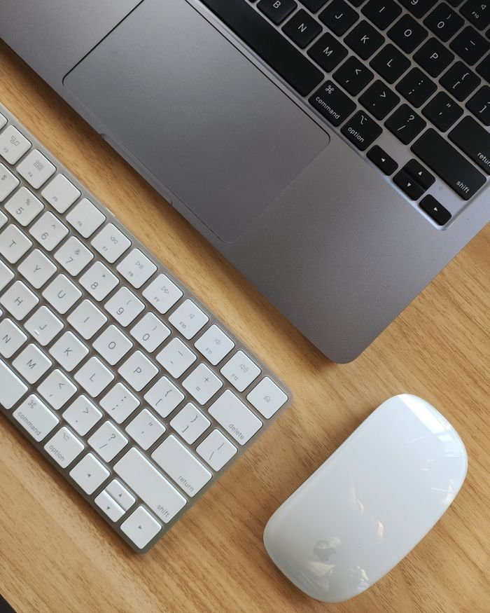 Top view of a sleek workspace featuring a laptop, keyboard, and mouse on a wooden desk.